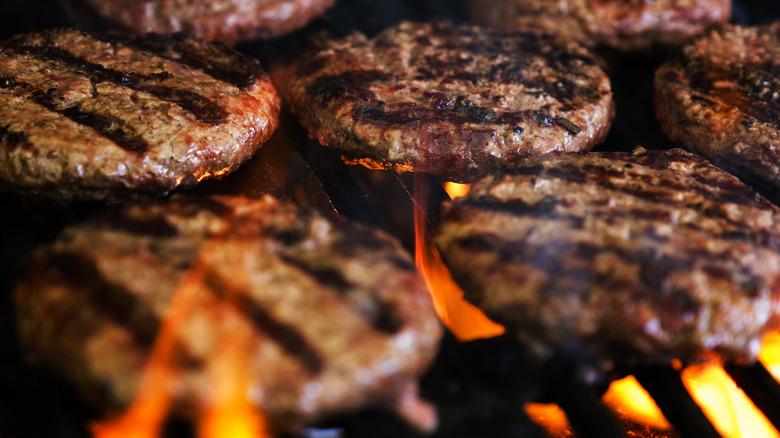 hamburger patties on a fiery grill