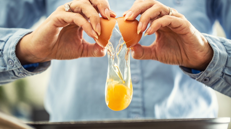 Hands cracking egg into pan