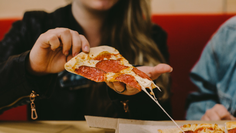 person grabbing slice of pizza 