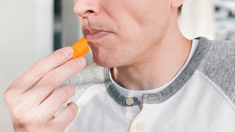 frowning man eating baby carrot