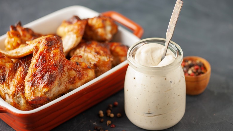 Jar of Alabama white sauce with dish of chicken wings